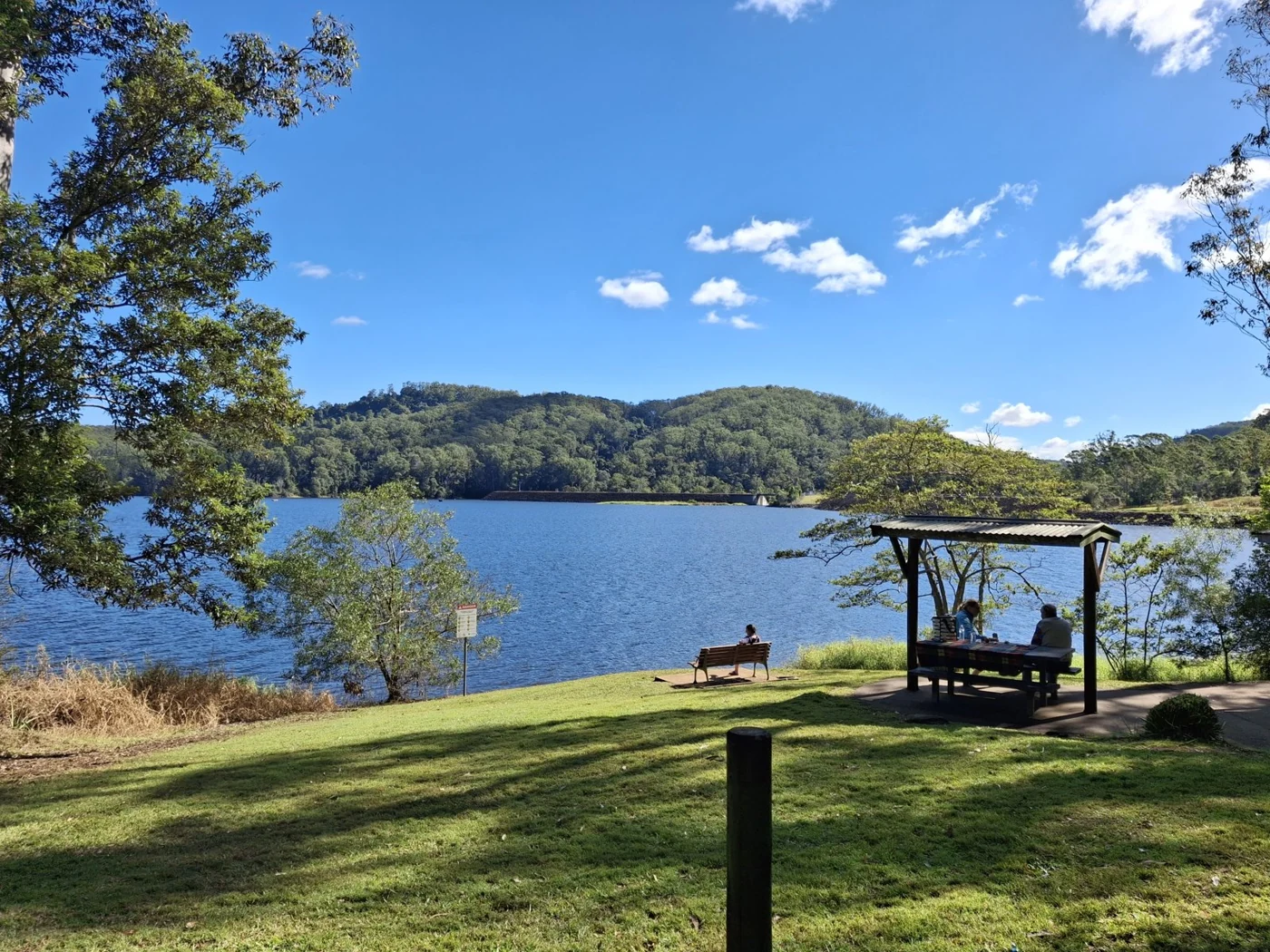 Reservoir shoreline with hills and a shaded lakeside shelter
